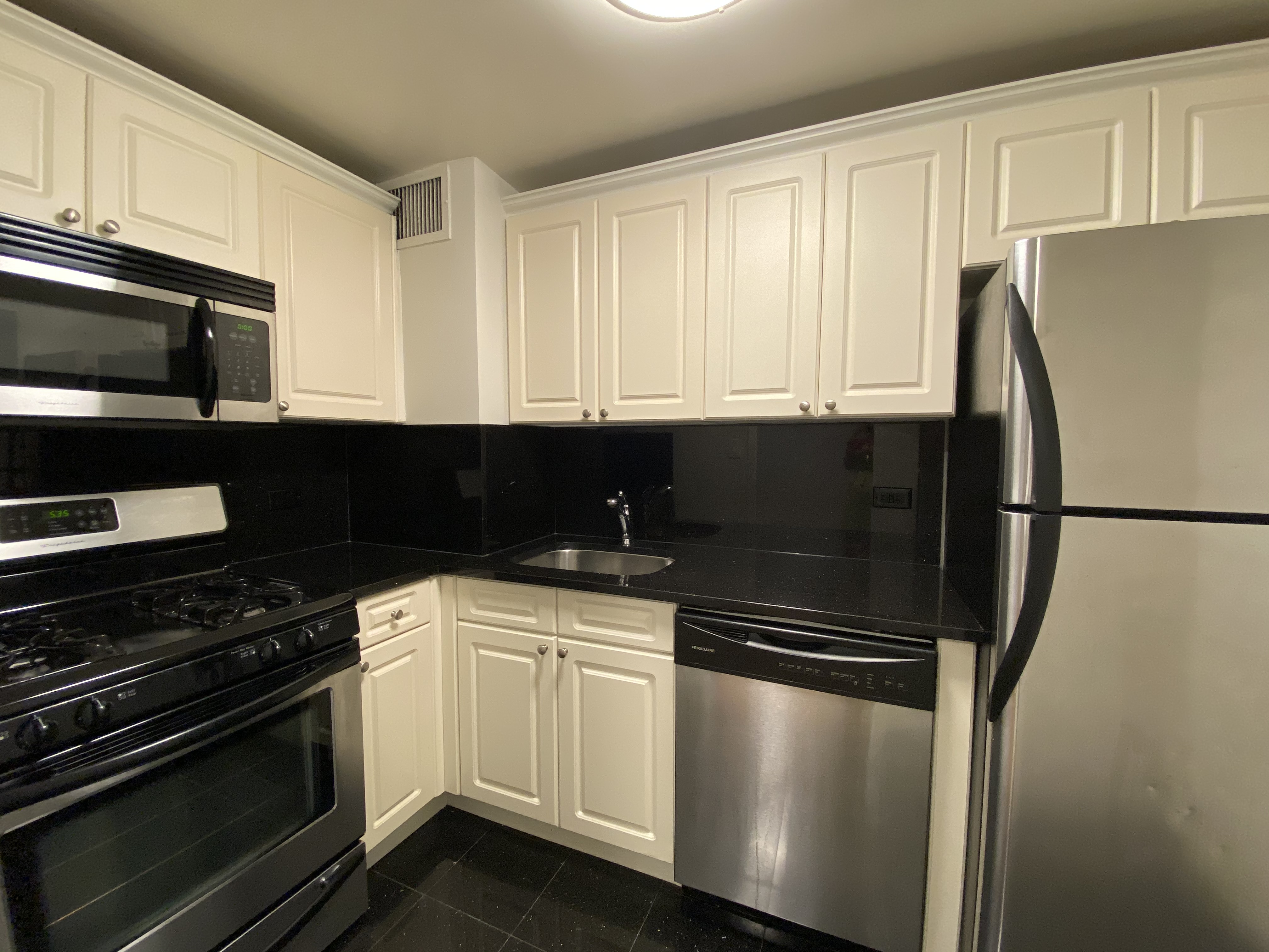 a kitchen with granite countertop white cabinets stainless steel appliances and sink