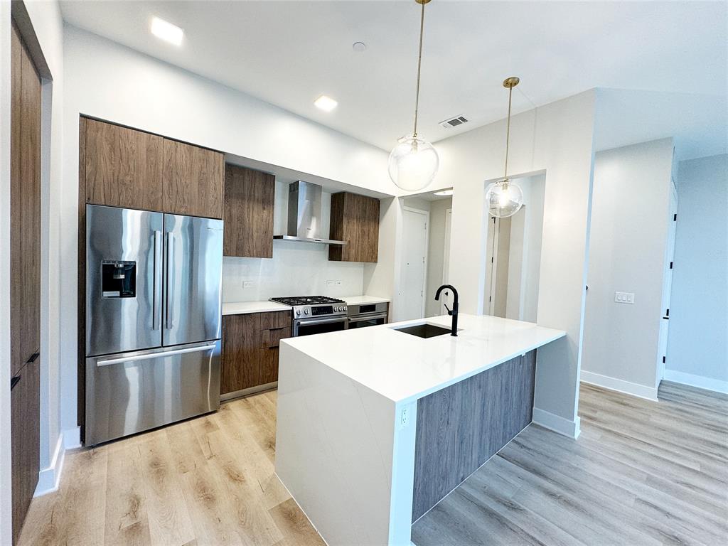 a kitchen with kitchen island a sink stainless steel appliances and refrigerator