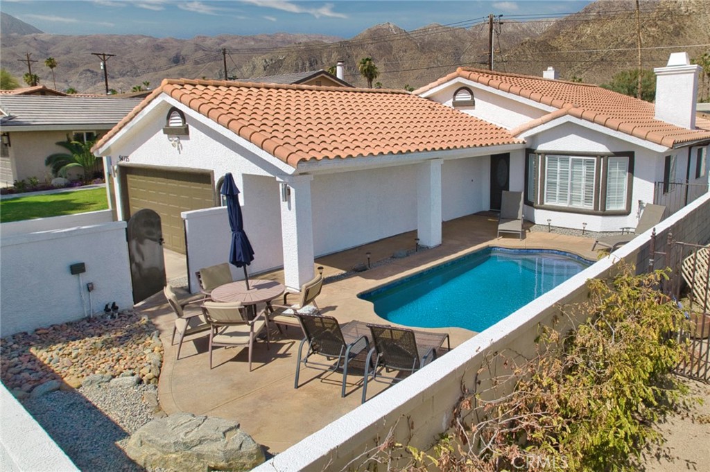 a view of a house with pool and chairs