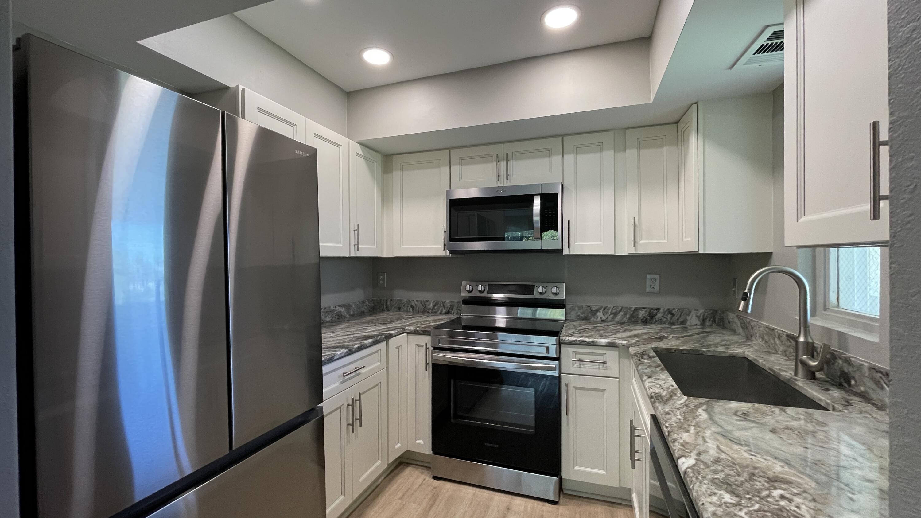 a kitchen with stainless steel appliances granite countertop a stove a sink and a refrigerator