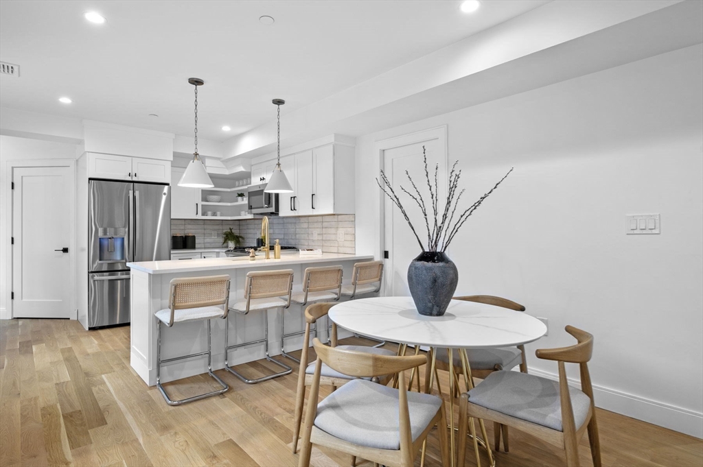 a kitchen with stainless steel appliances a dining table chairs and a refrigerator