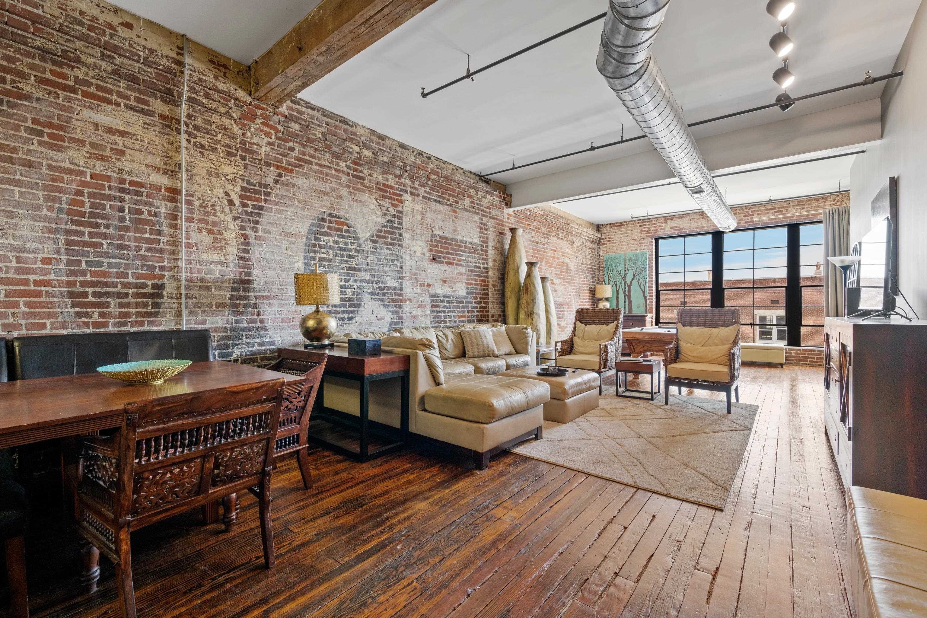 Living room with hardwood / wood-style floors, beam ceiling, brick wall, and track lighting