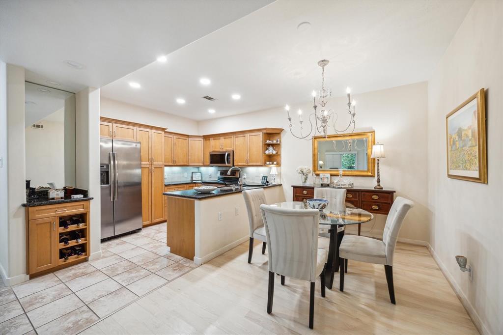 a kitchen with stainless steel appliances kitchen island granite countertop a table chairs and a refrigerator