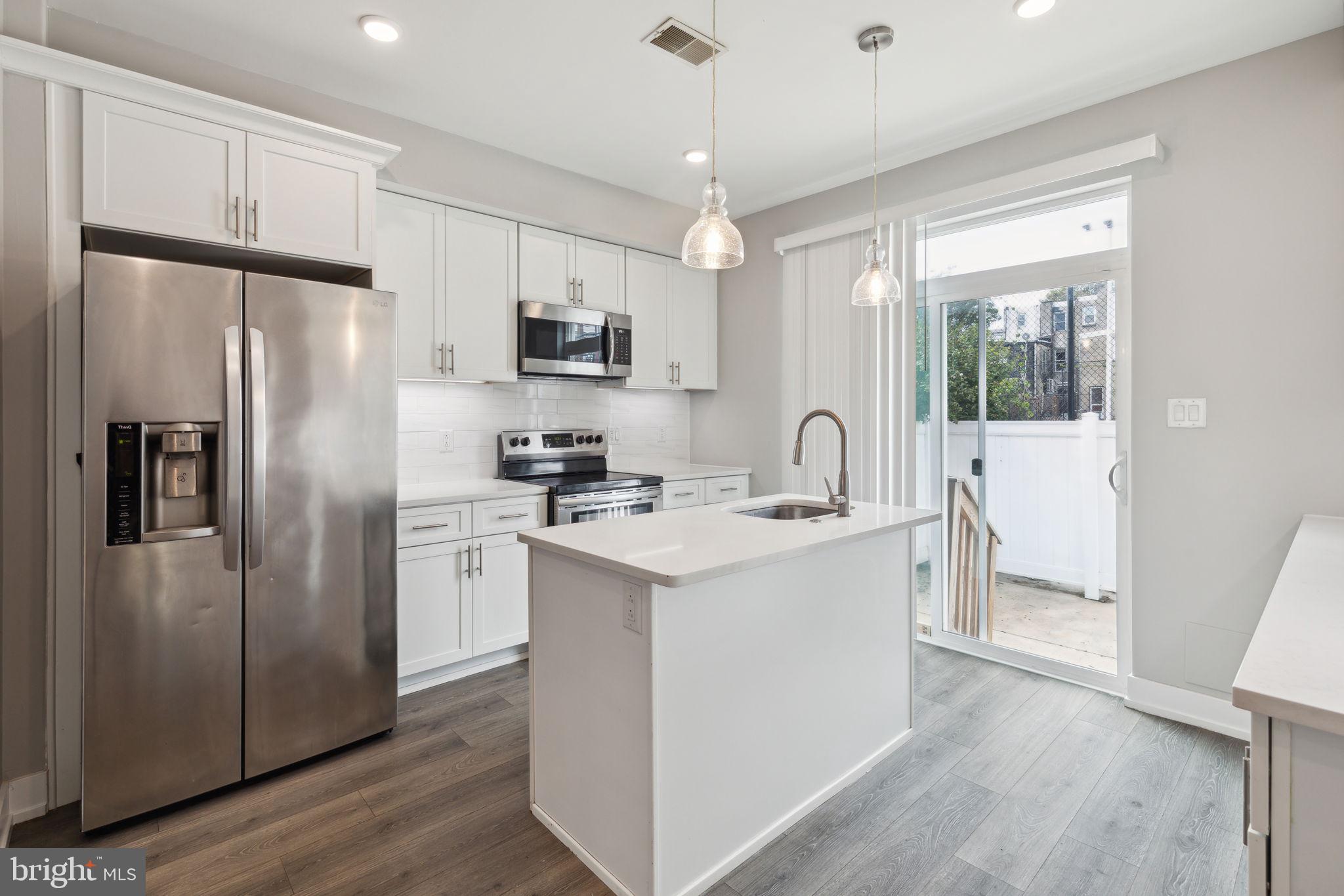 a kitchen with stainless steel appliances a sink stove refrigerator and cabinets