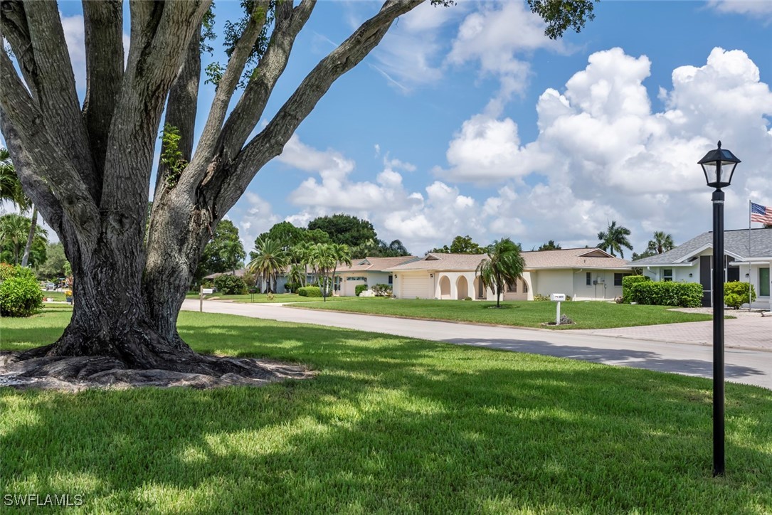 a view of a fountain in front of a big house with a big yard and large trees