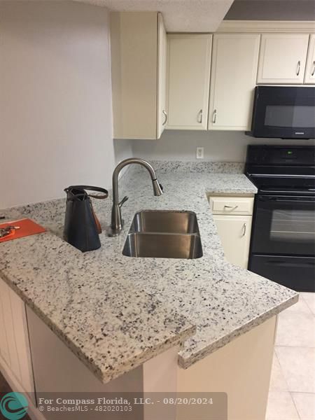 a kitchen with kitchen island a stove a sink and white cabinets