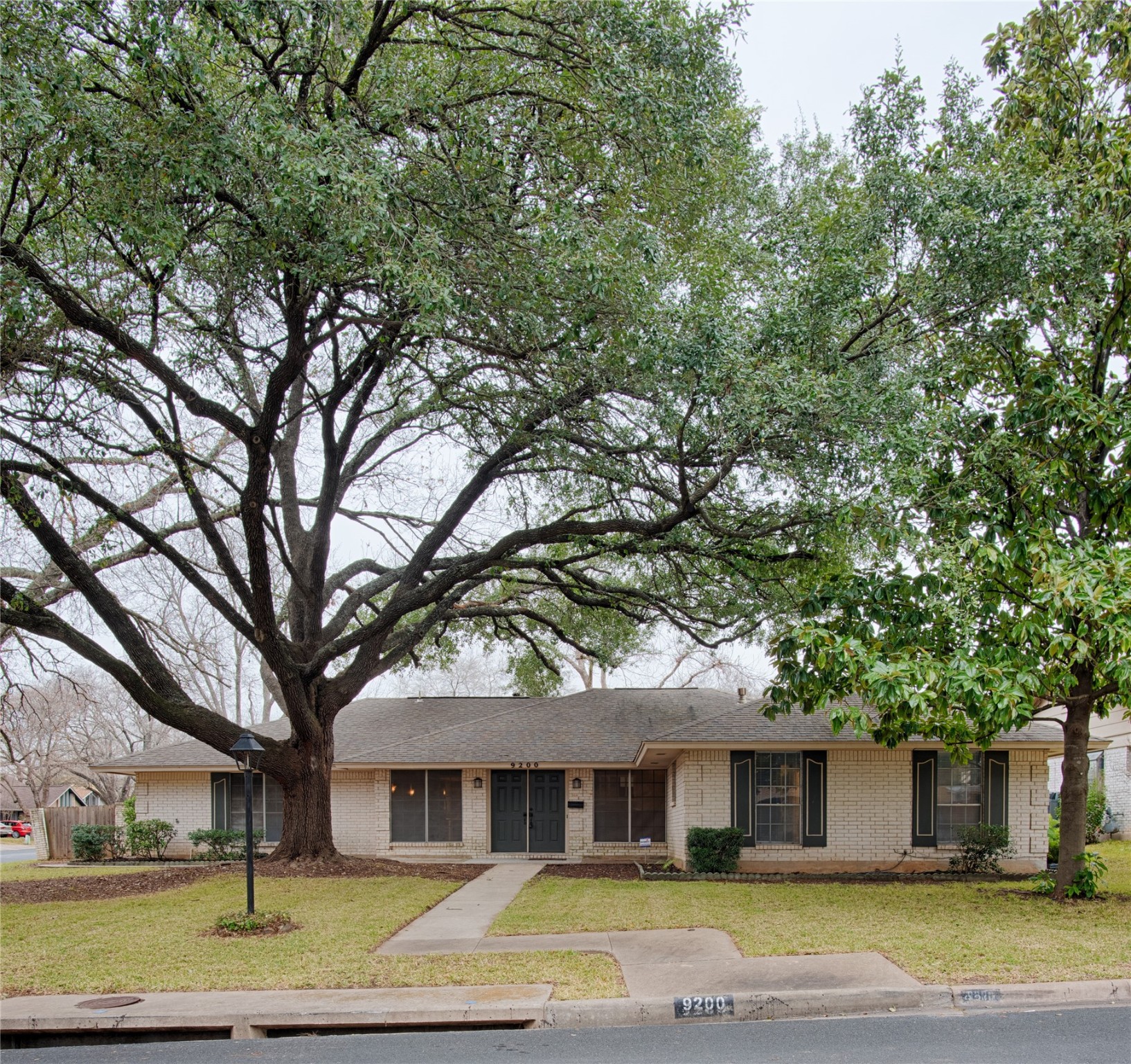 a view of a house with a yard and large trees