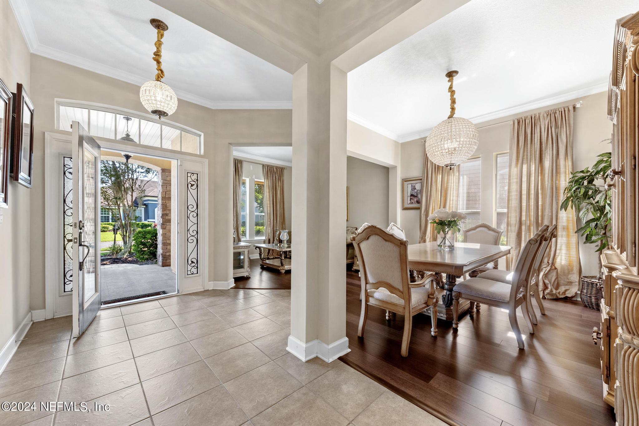 a view of a dining room and livingroom with furniture wooden floor a chandelier