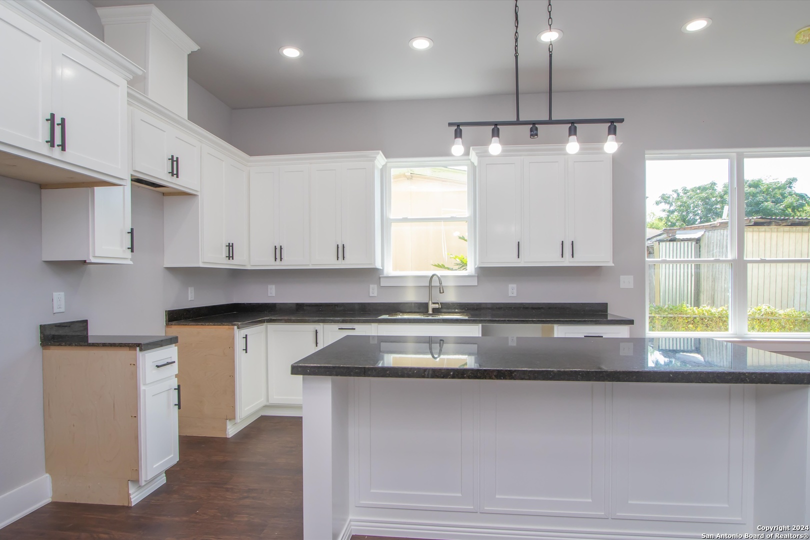 a kitchen with kitchen island granite countertop a sink window and cabinets