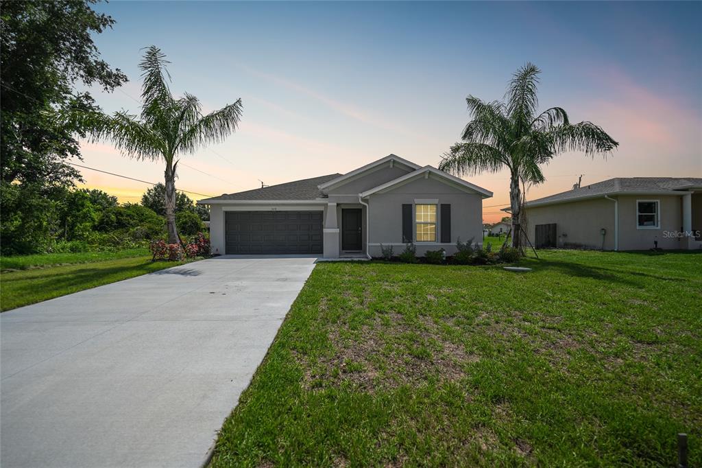 a front view of house with a yard and palm trees