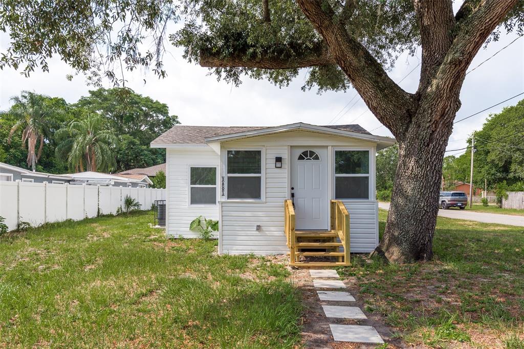 a view of a house with backyard and a tree