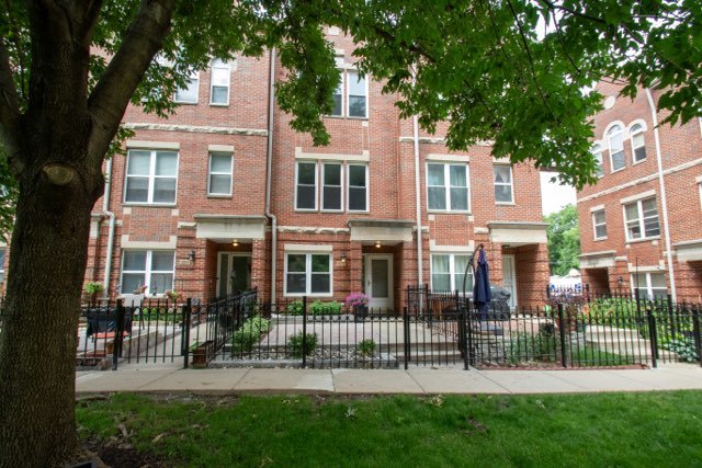 a view of a brick house with a yard and a fountain