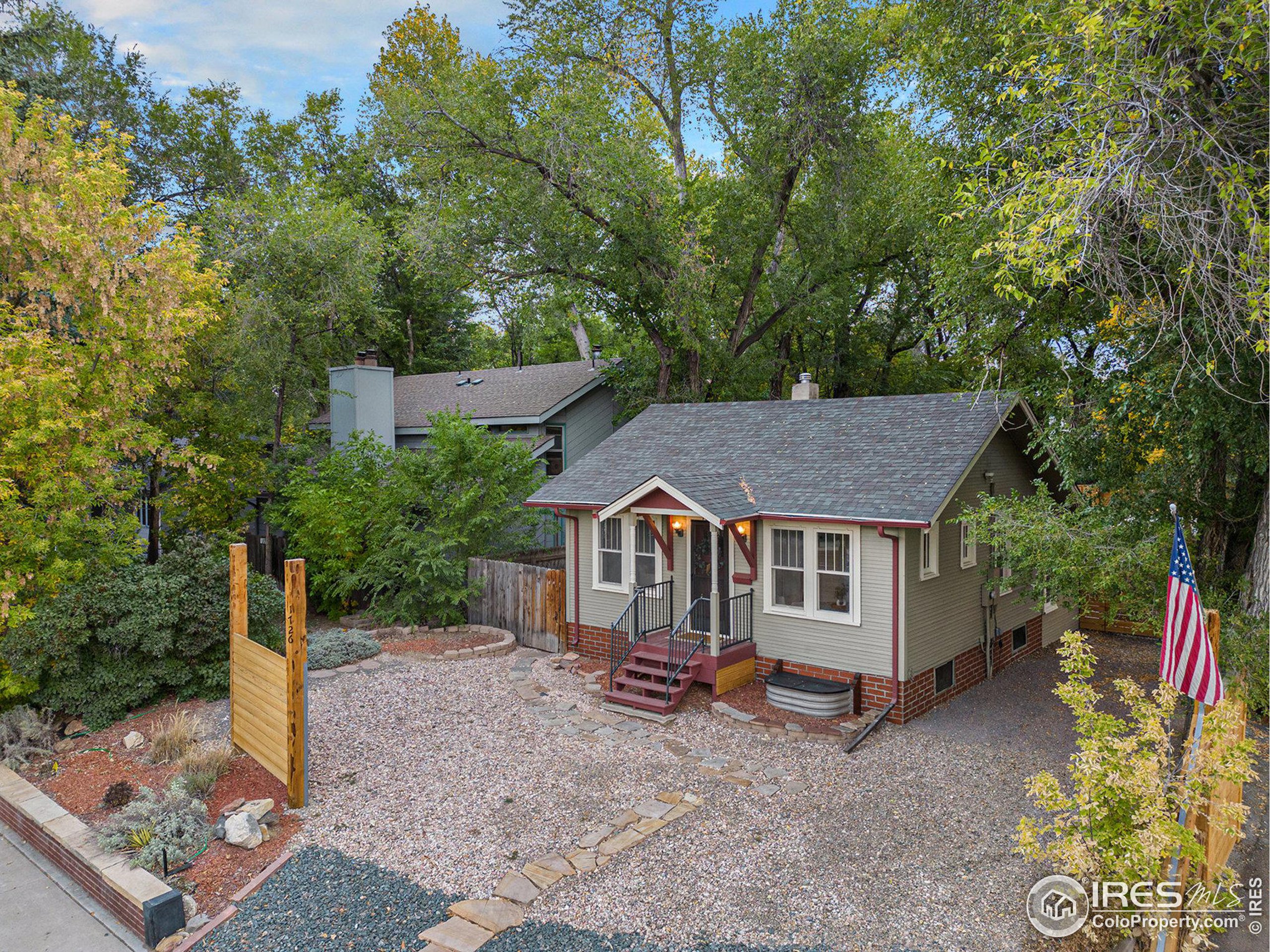 a view of a house with a yard plants and large tree