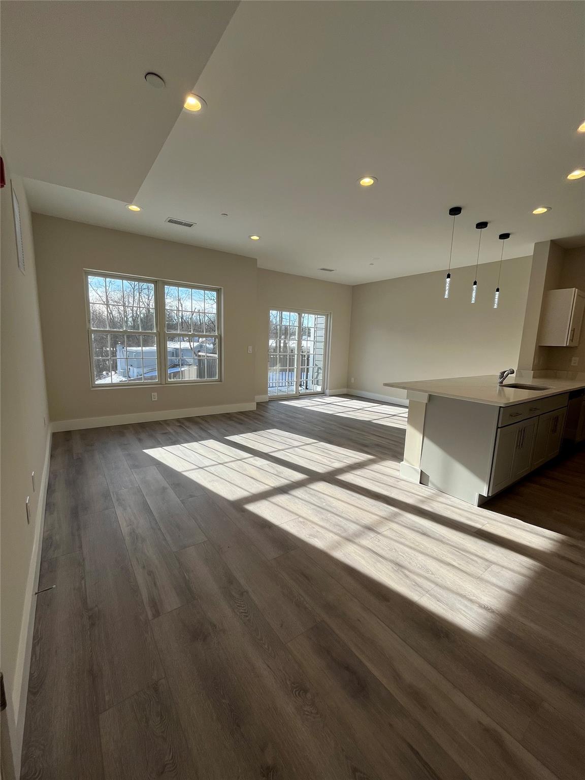 a view of an empty room with window and wooden floor