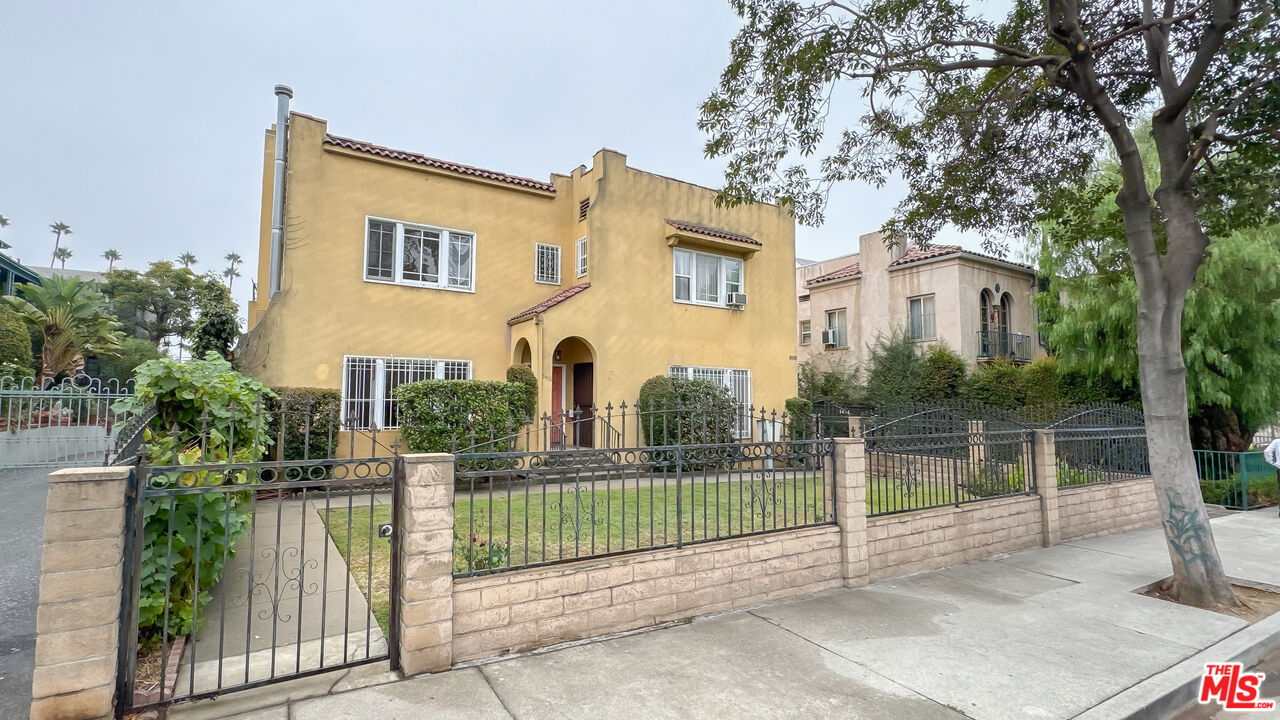 a view of a house with wooden fence next to a yard