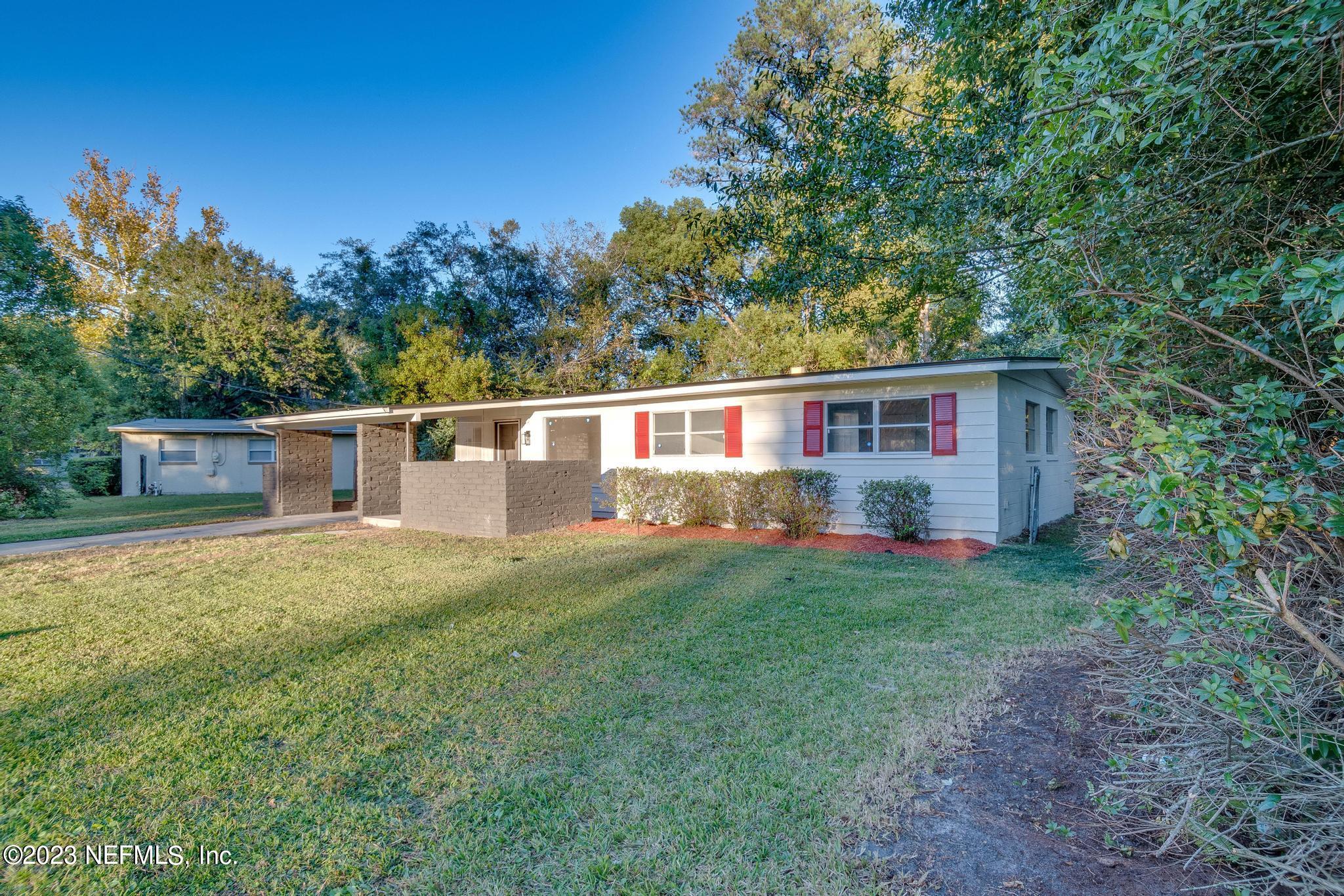 a view of a house with backyard and a tree