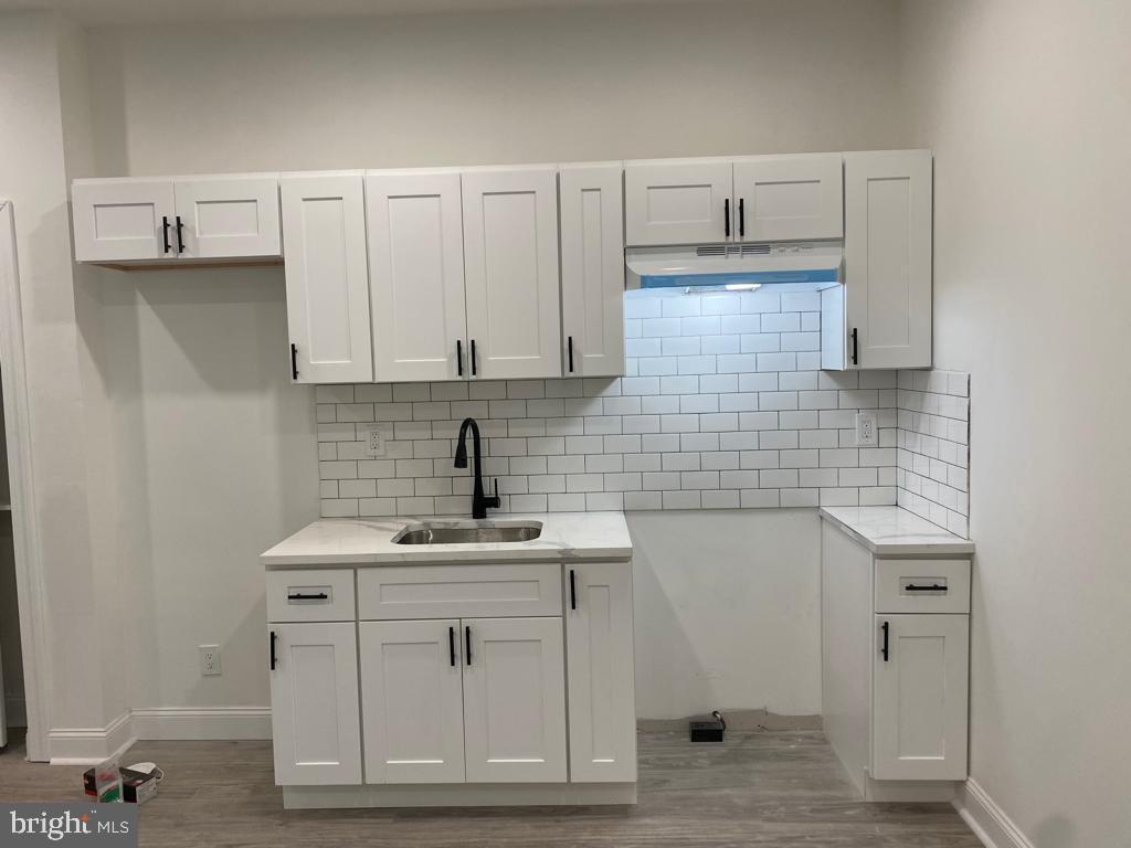 a view of cabinets a sink and a stove with wooden floor