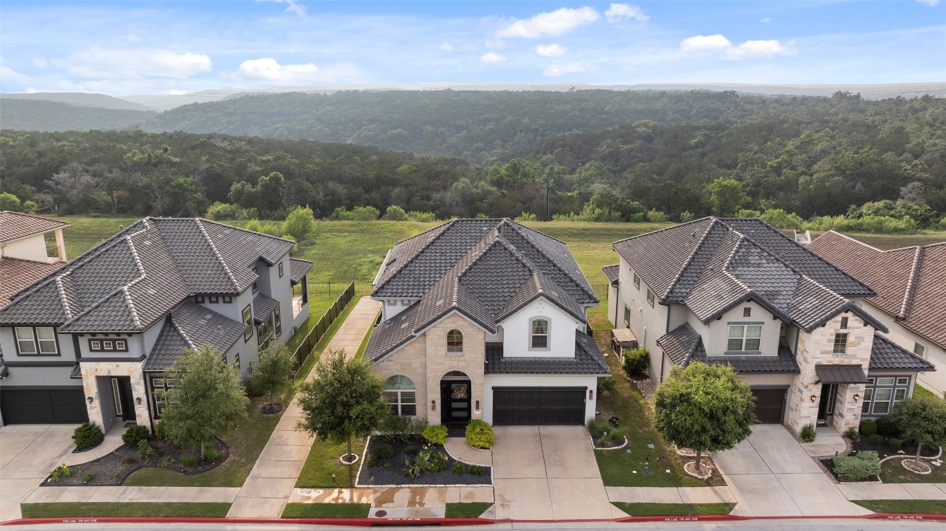 a view of a big house with a big yard plants and large trees