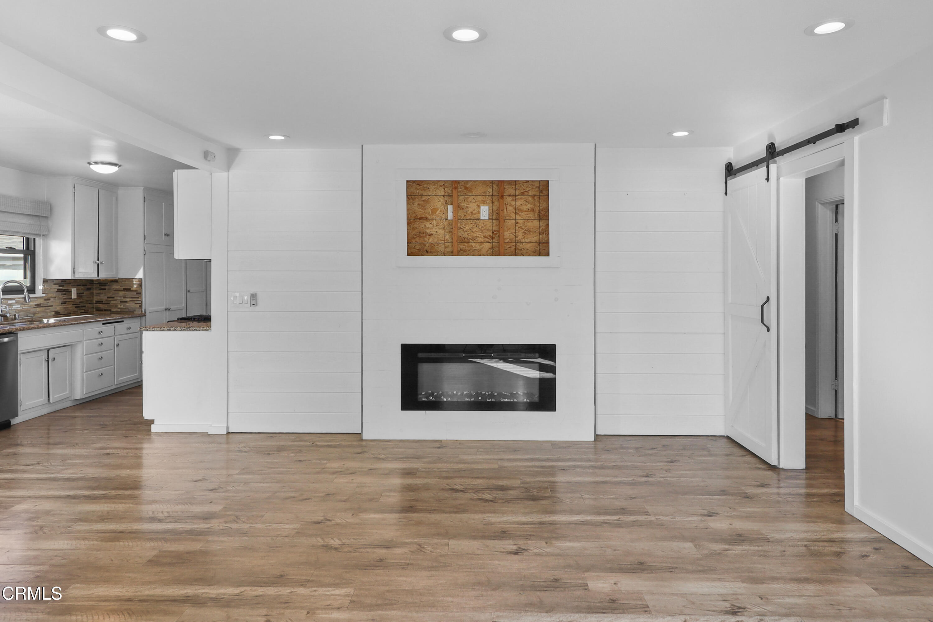 a view of a kitchen an empty room and kitchen with wooden floor