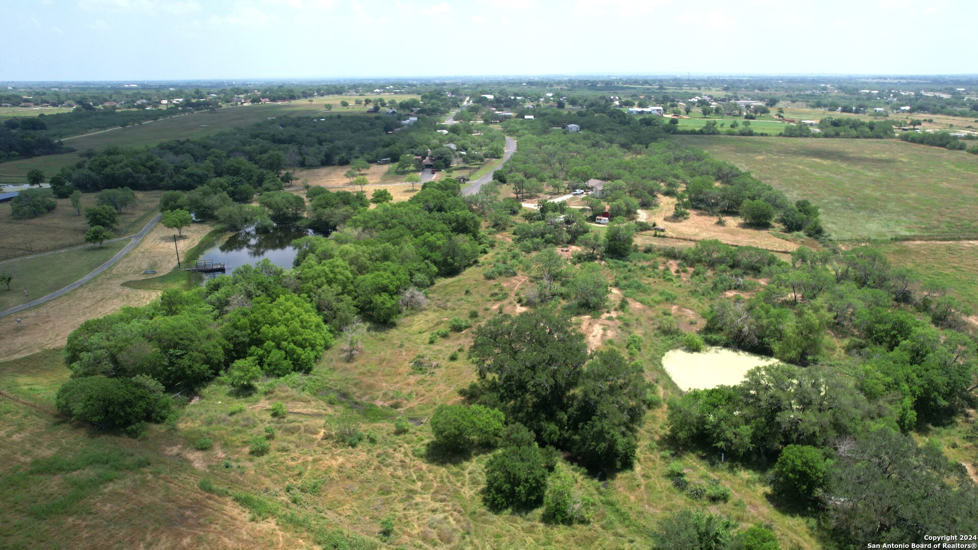 an aerial view of a houses with a yard and lake view