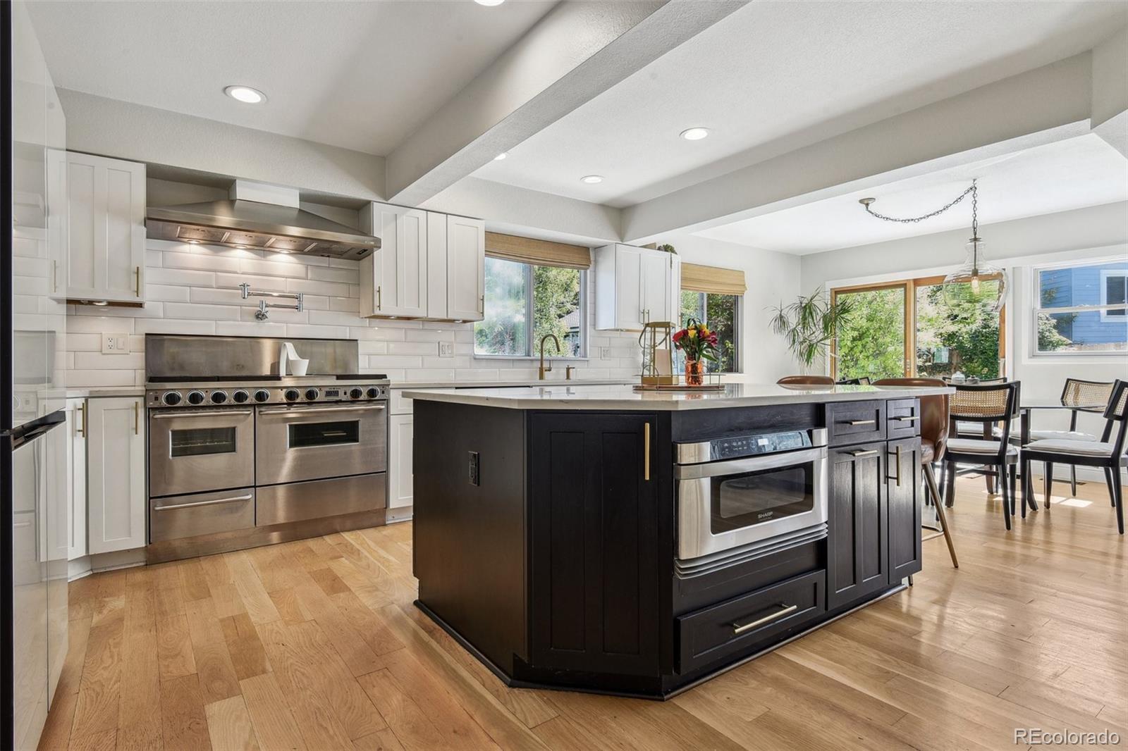 a kitchen with stainless steel appliances a stove a sink a oven a dining table and chairs