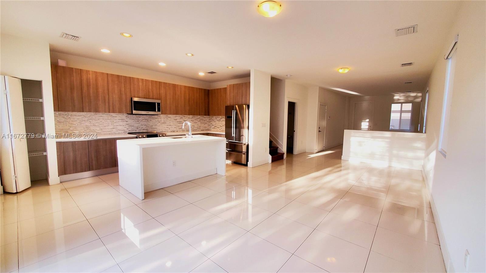 a view of a kitchen with stainless steel appliances kitchen island granite countertop a refrigerator and a sink