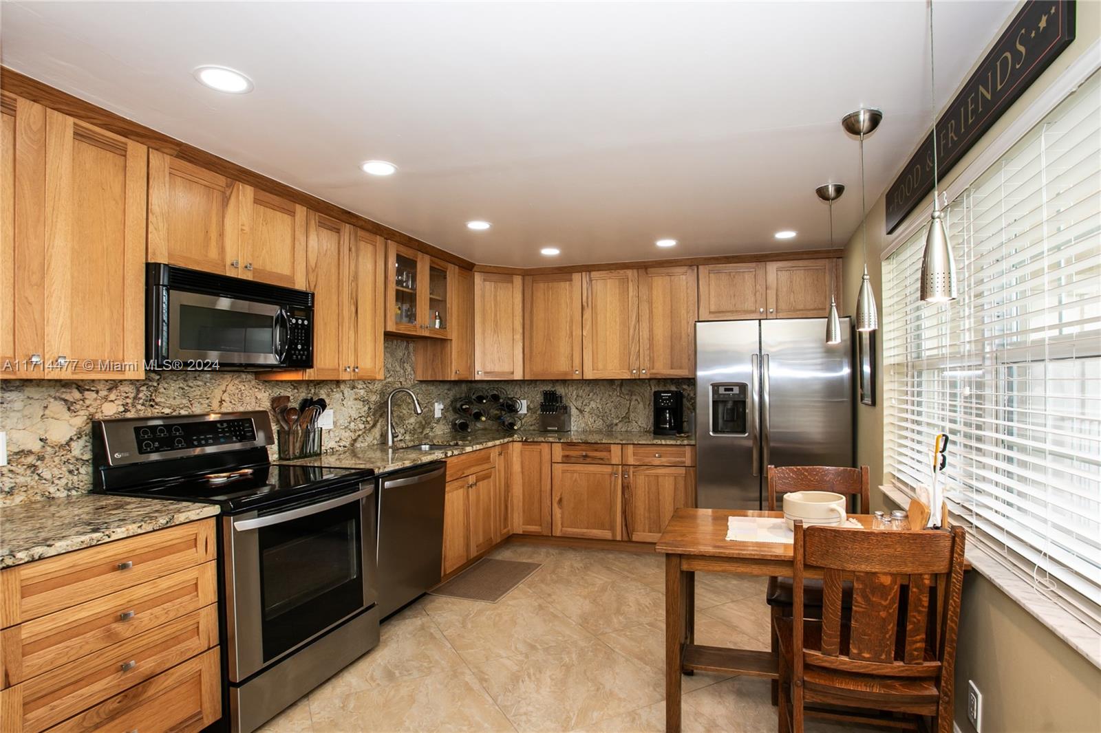 a kitchen with stainless steel appliances granite countertop a stove top oven a sink dishwasher a microwave oven and a refrigerator with wooden floor