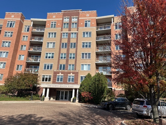 a front view of a building with lot of trees around