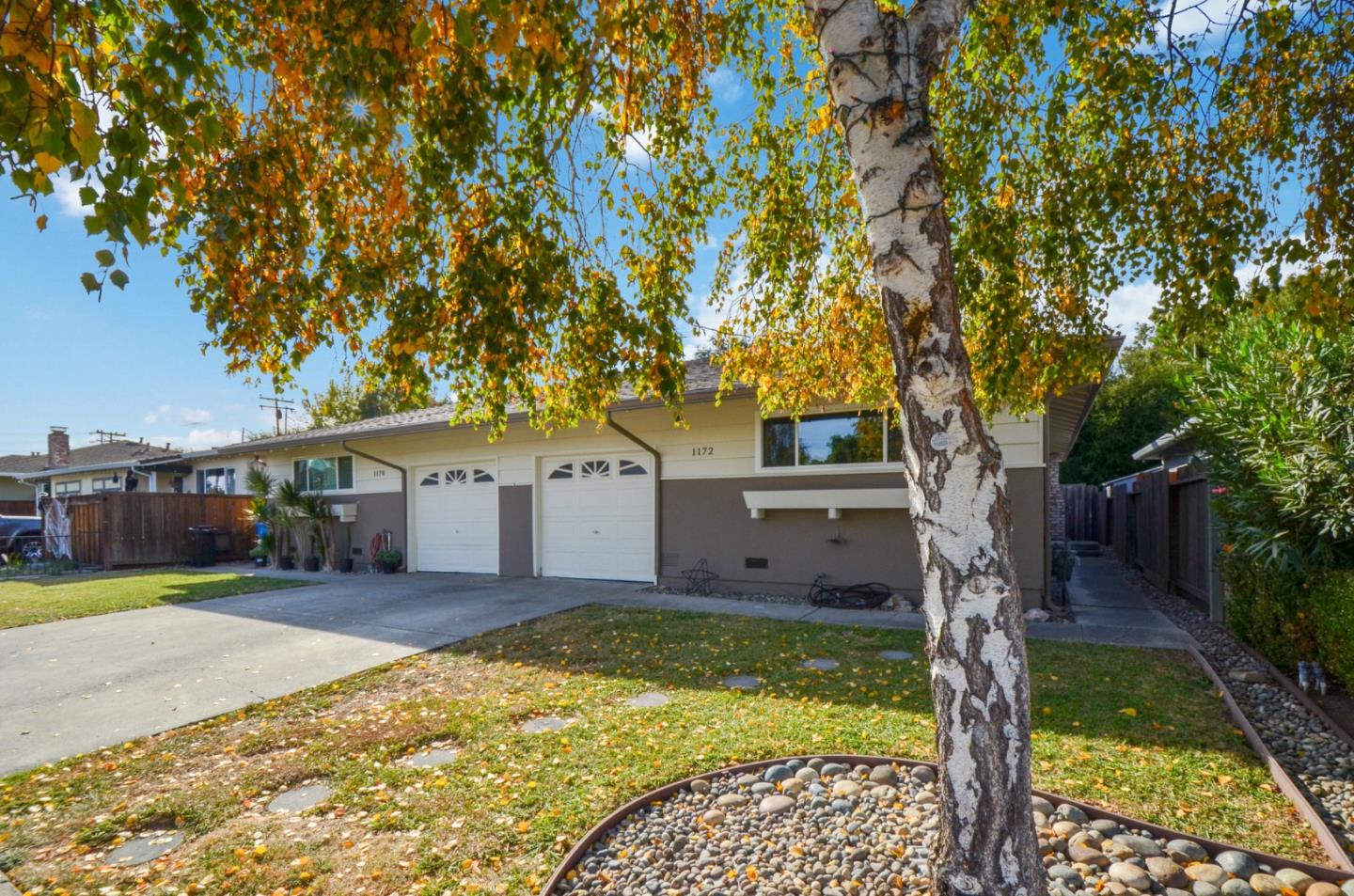 a front view of a house with a yard and large tree