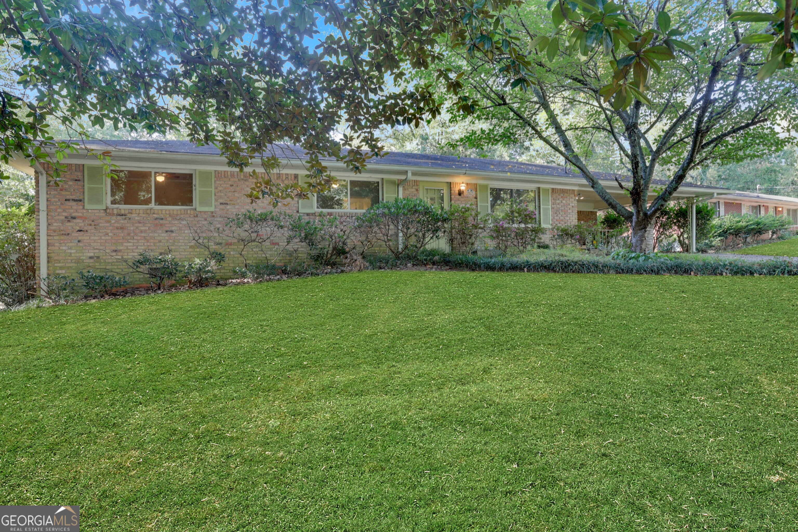 a view of a house next to a big yard and large trees