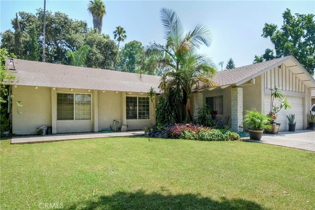 a front view of a house with a yard and potted plants