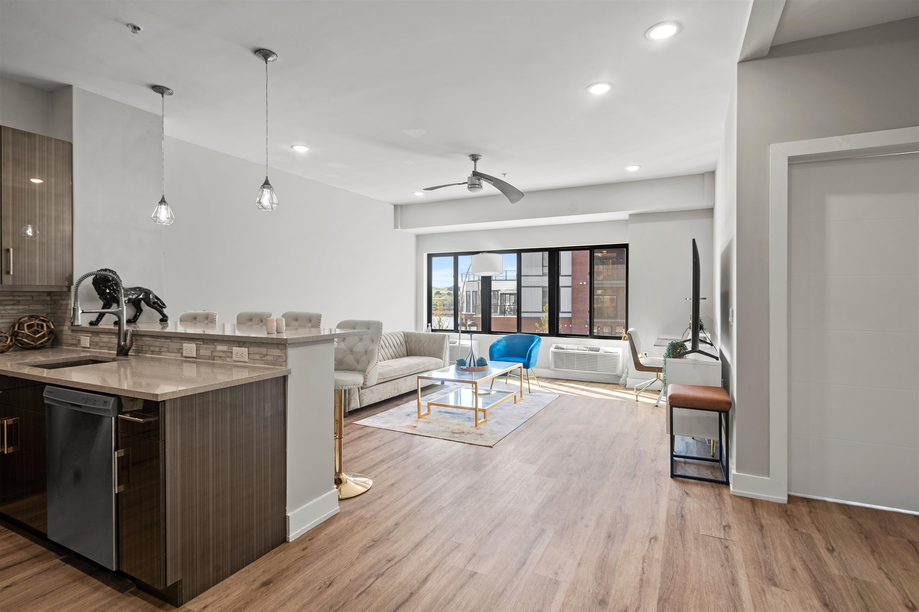 a living room with stainless steel appliances granite countertop a sink dishwasher and a stove with wooden floor