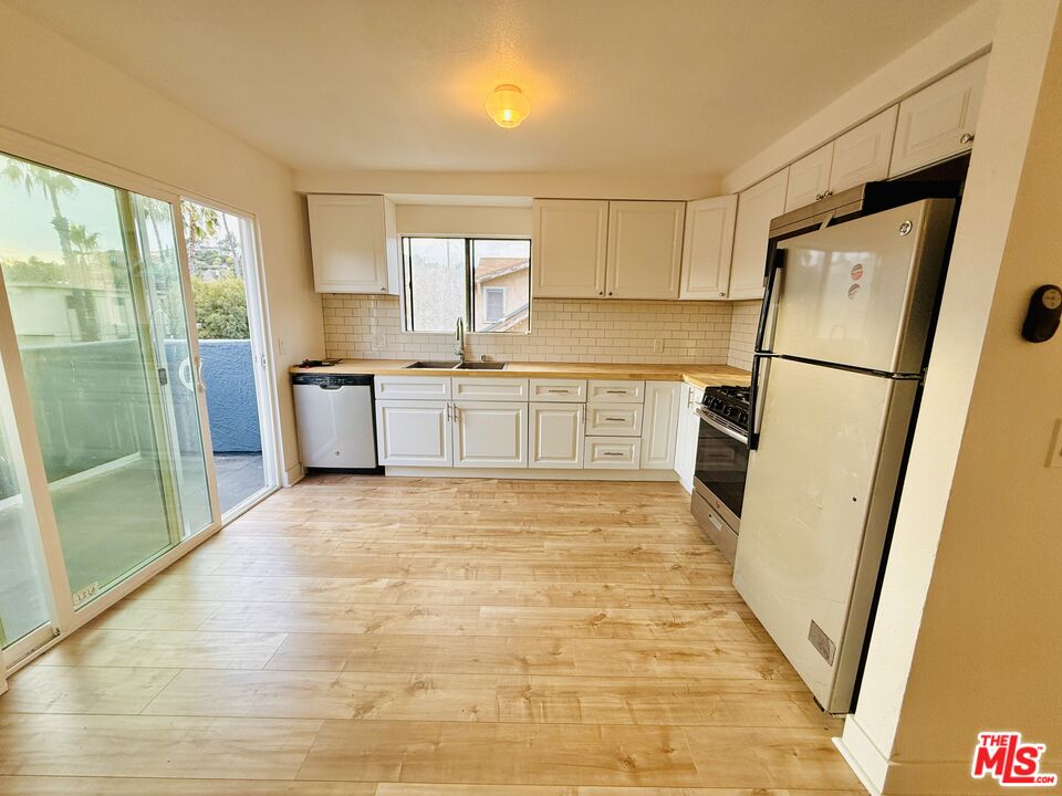 a large white kitchen with stainless steel appliances a refrigerator a stove a sink and dishwasher