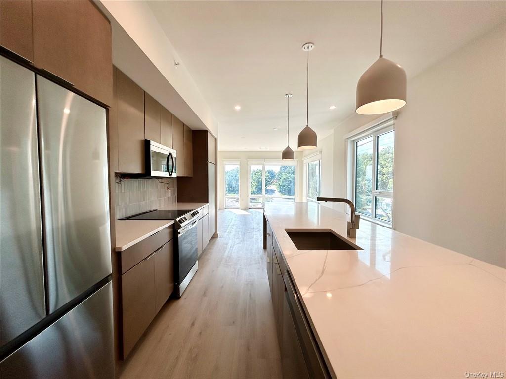 a kitchen with kitchen island a counter top space a sink a refrigerator and wooden floor