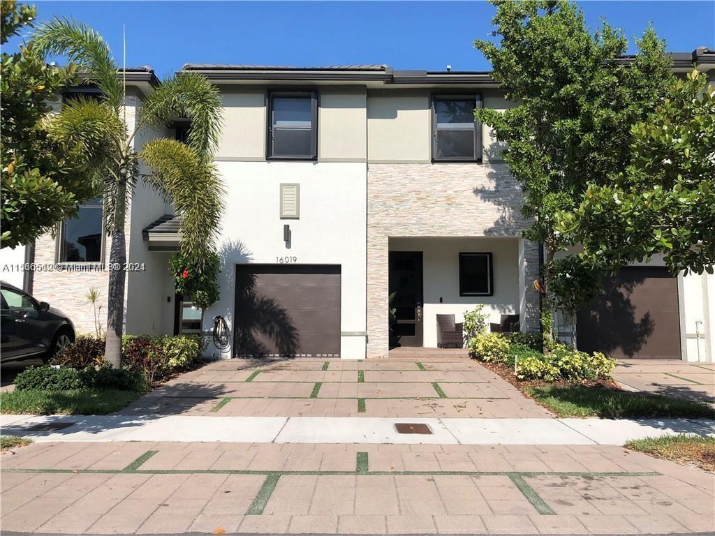 a front view of a house with a yard and potted plants