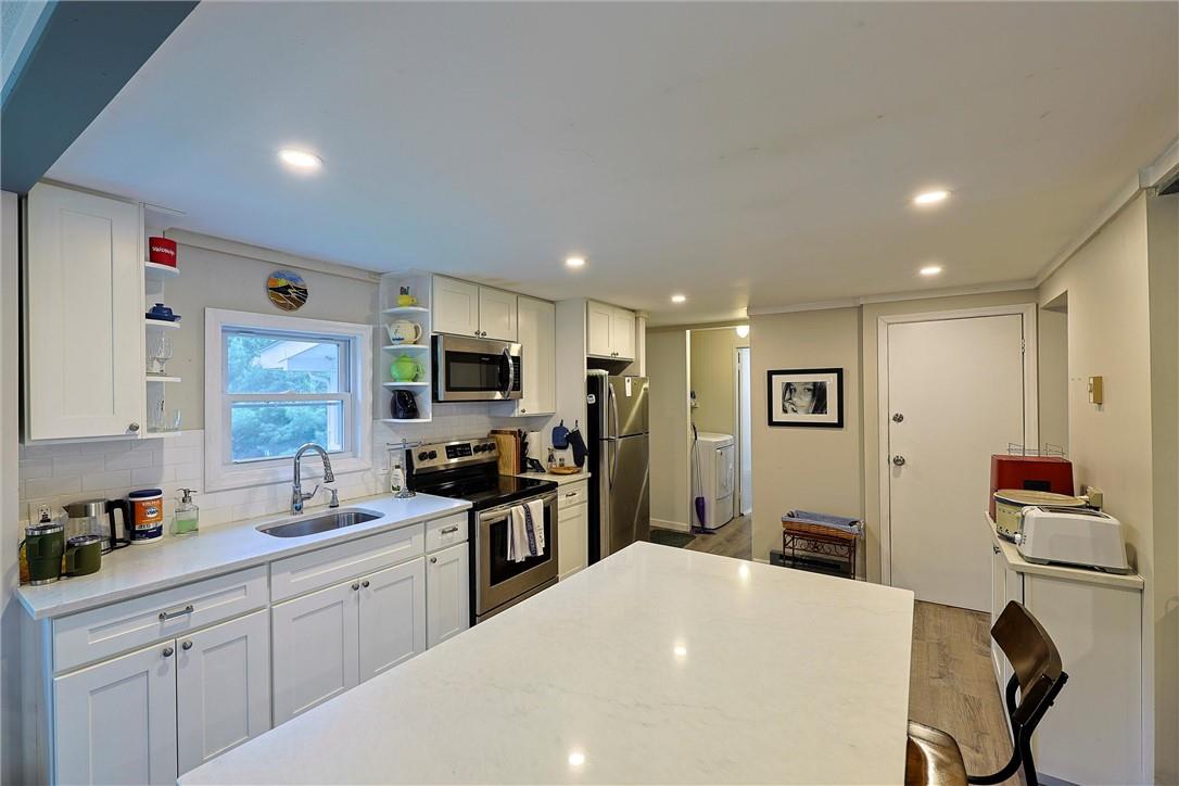 Kitchen with appliances with stainless steel finishes, sink, and white cabinets