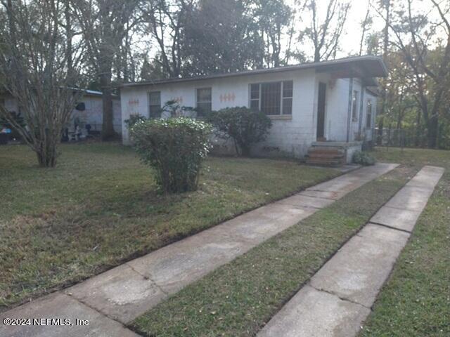 a view of a house with a yard and large tree