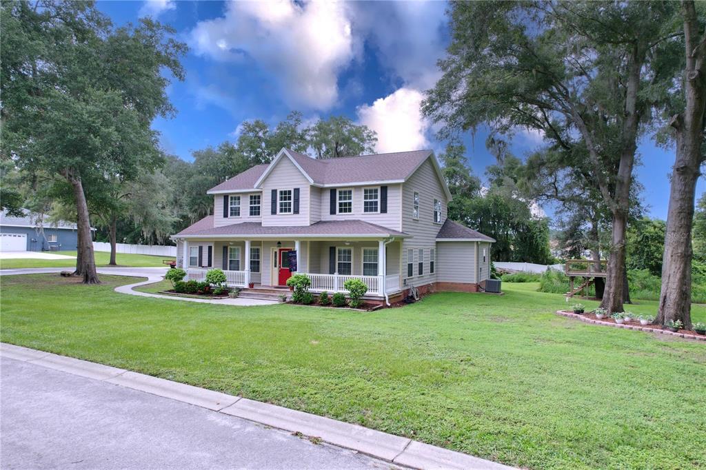 a view of a house with a big yard and large trees