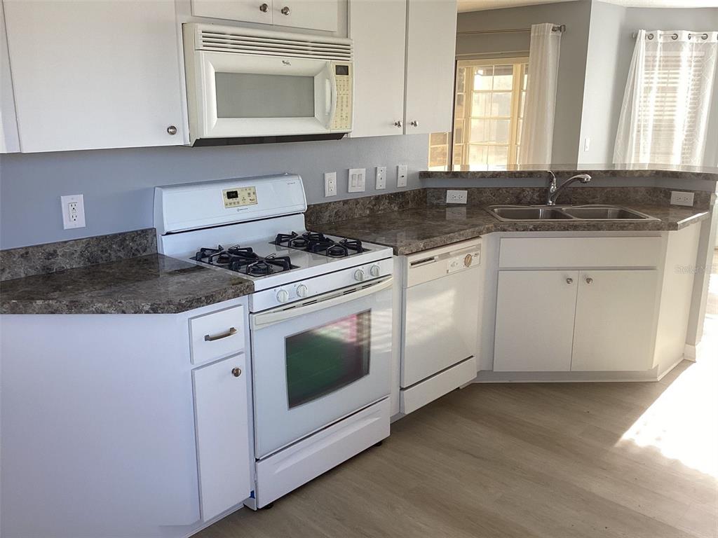 a kitchen with granite countertop white cabinets and white appliances