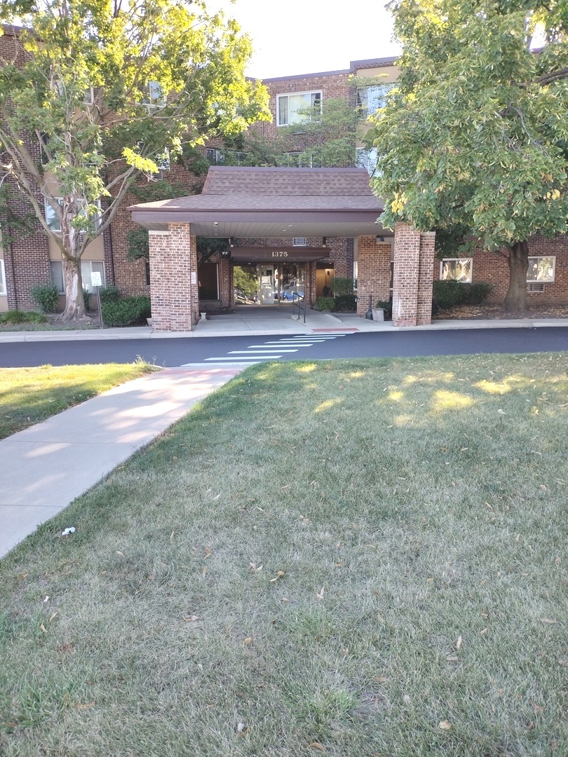 a view of a house with a yard and large tree