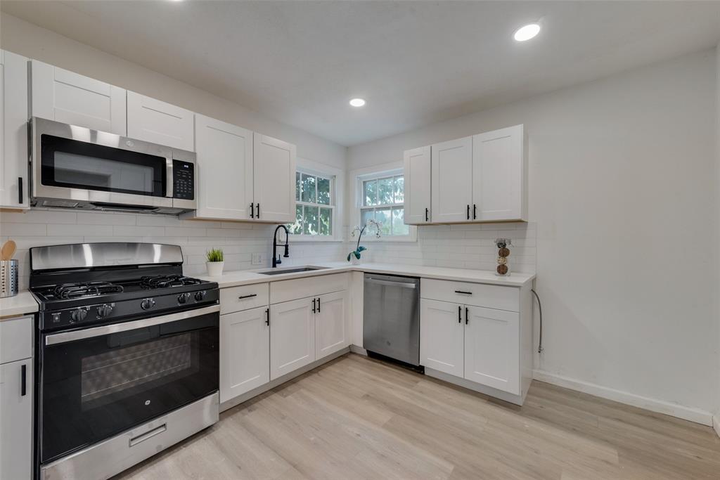 a kitchen with granite countertop white cabinets and stainless steel appliances