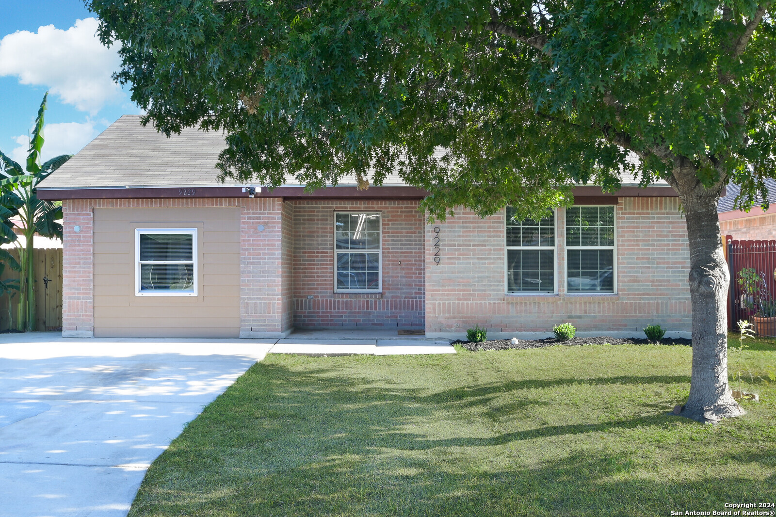 a front view of a house with a yard and trees