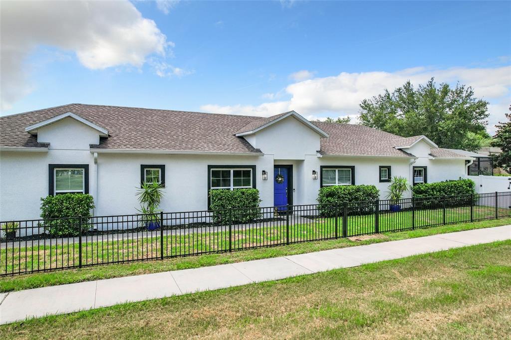 a view of a house in front of a yard with plants and wooden fence