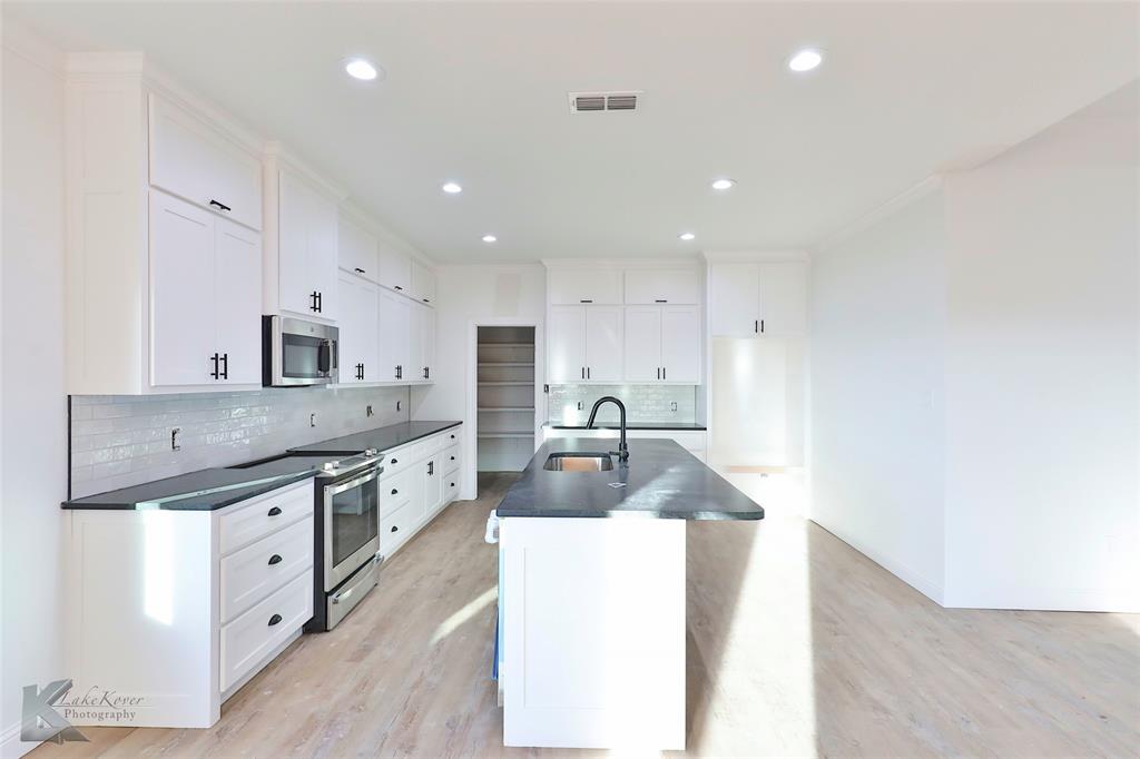 a large kitchen with stainless steel appliances granite countertop a sink stove and refrigerator