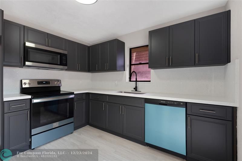 a kitchen with stainless steel appliances a sink a stove a microwave and cabinets