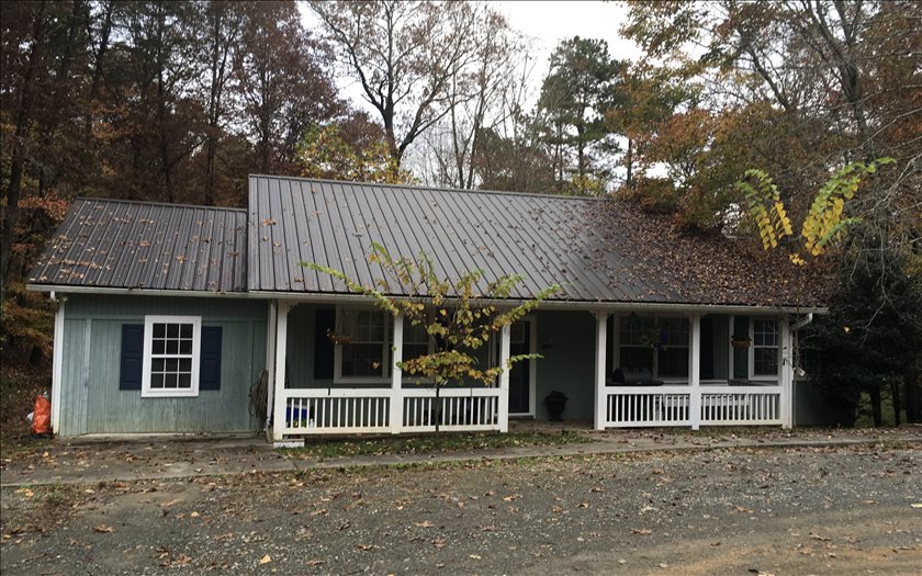 a front view of a house with a large tree