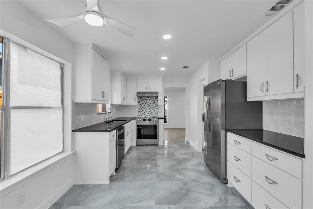 a modern kitchen with stainless steel appliances granite countertop a refrigerator and a stove top oven