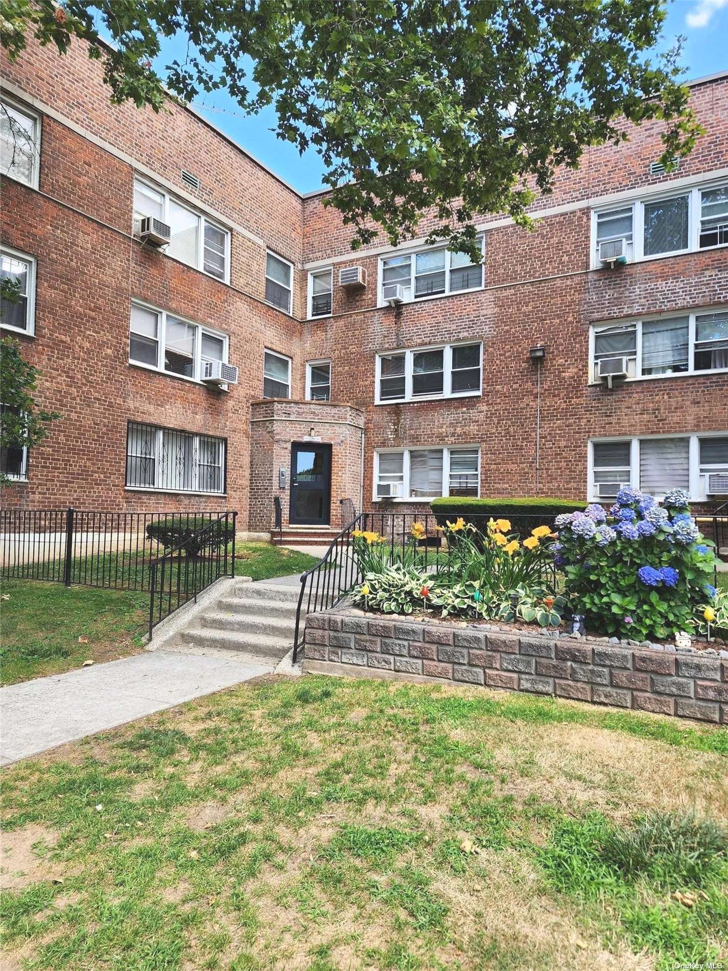 a front view of a residential apartment building with a yard and plants