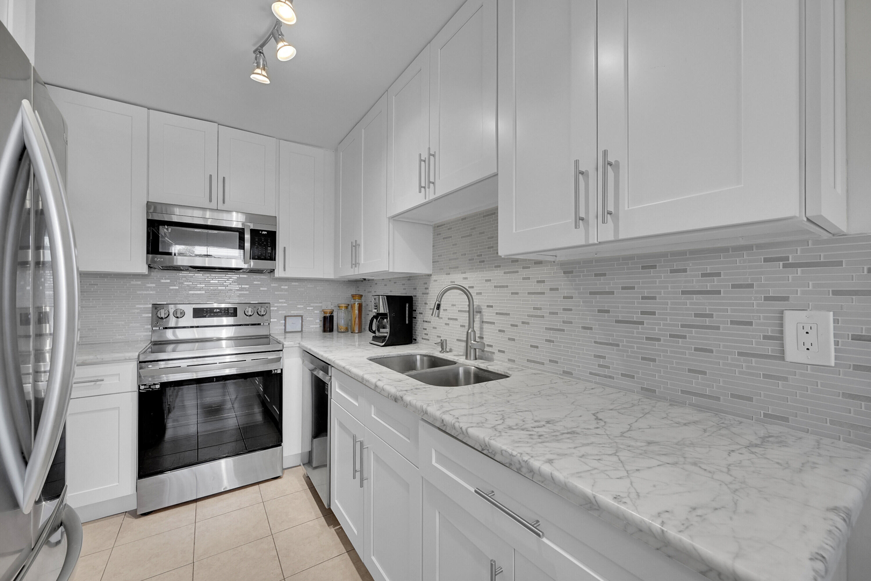 a kitchen with granite countertop white cabinets stainless steel appliances and a sink