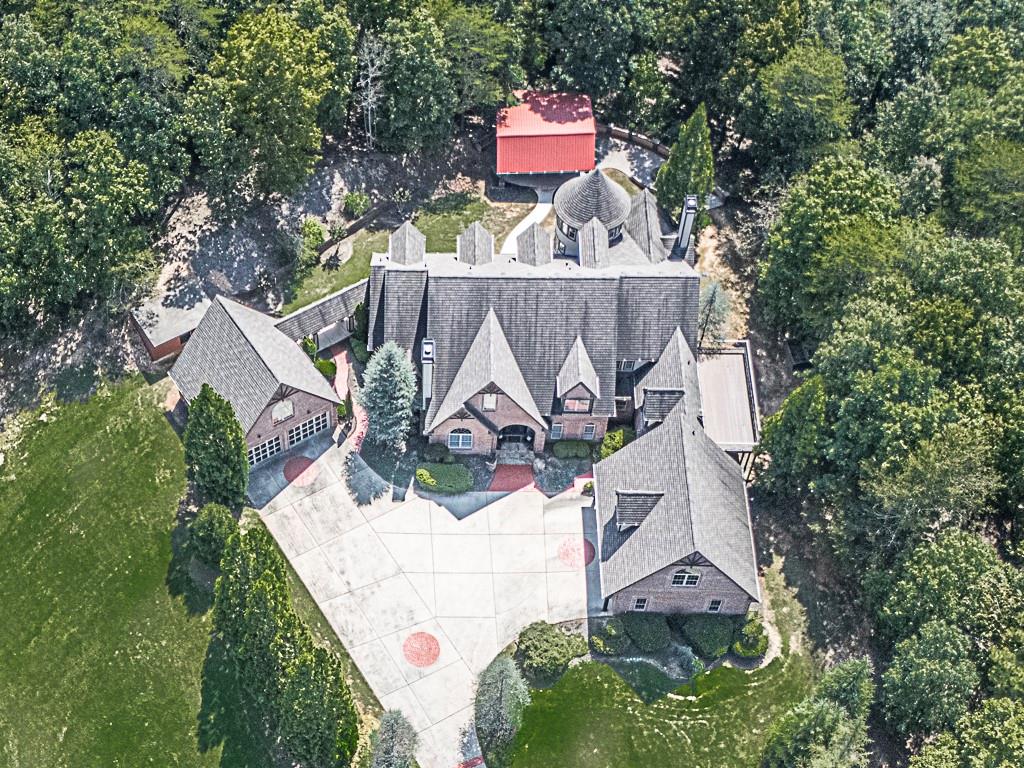 an aerial view of a house with swimming pool and large trees